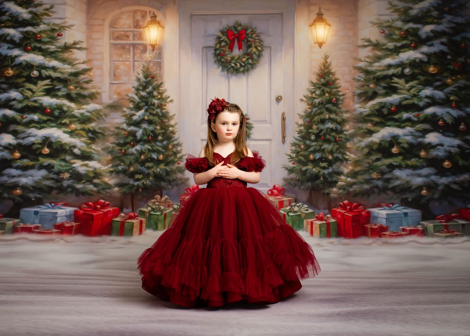 A festive holiday scene with a deep red tulle gown against snow-dusted evergreens and wrapped presents.