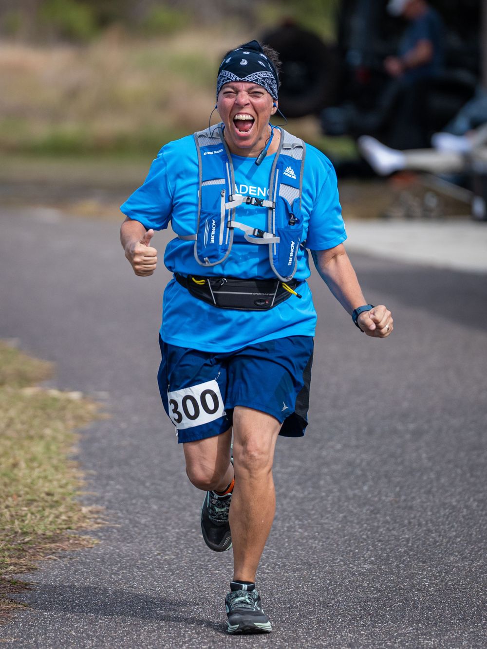 Enthusiastic runner in blue shirt shows excitement while running on paved course.