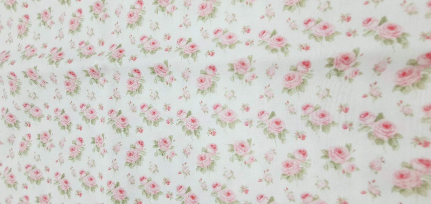 Delicate pink floral pattern on white fabric with small scattered roses and petals creating a vintage shabby chic design.