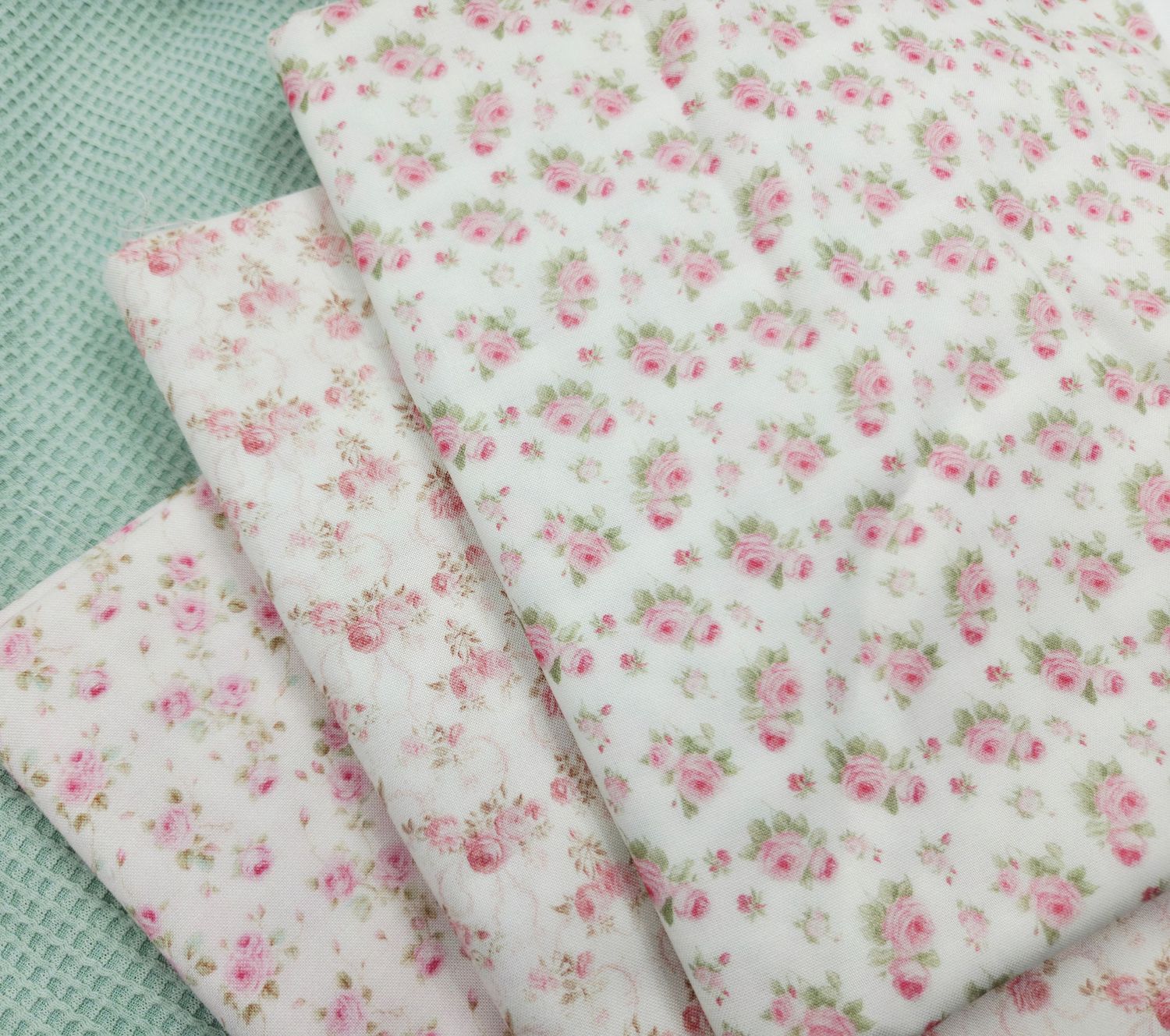 Delicate pink floral pattern fabric swatches arranged in a row on a mint green background.