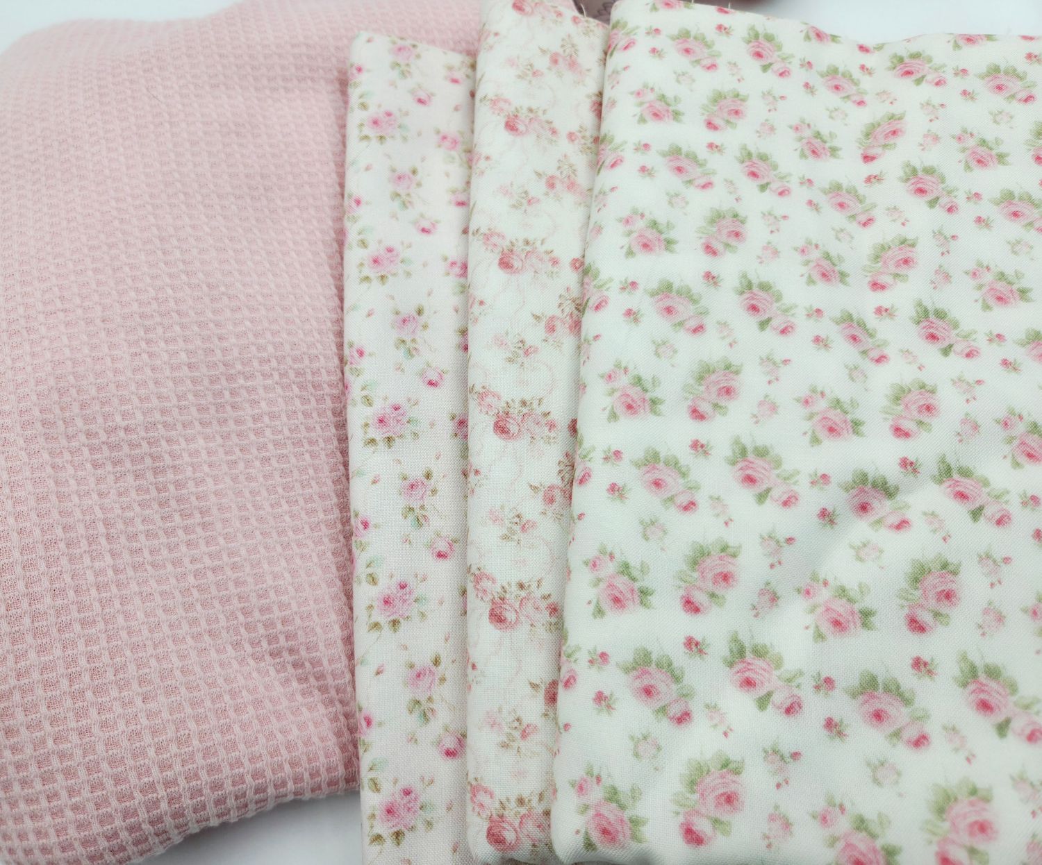 Pink waffle-textured fabric alongside white cotton material with delicate pink floral print pattern.