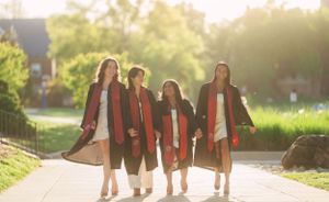 Group of graduates walking together at sunset in matching red and white stoles.