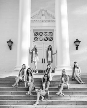 Black and white photo of graduates sitting on white columned building steps.