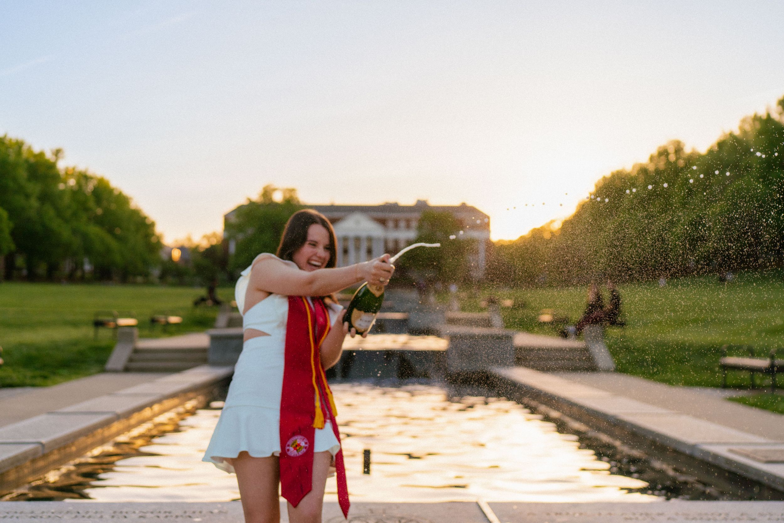 Graduation photoshoot at sunset with steps and warm lighting in background.
