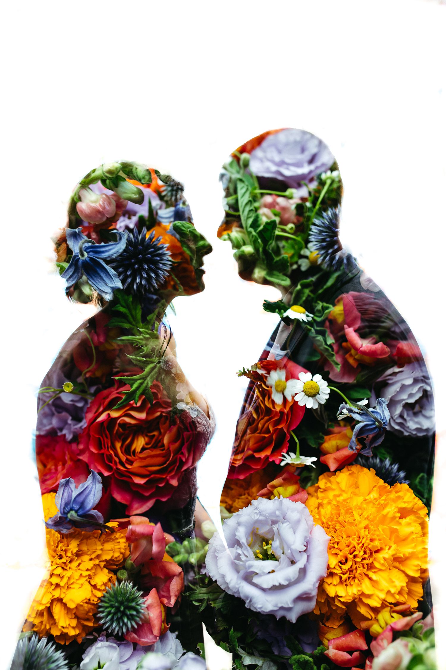 Double exposure silhouette portrait overlaid with vibrant flowers including roses, marigolds and blue thistles in mixed colors.