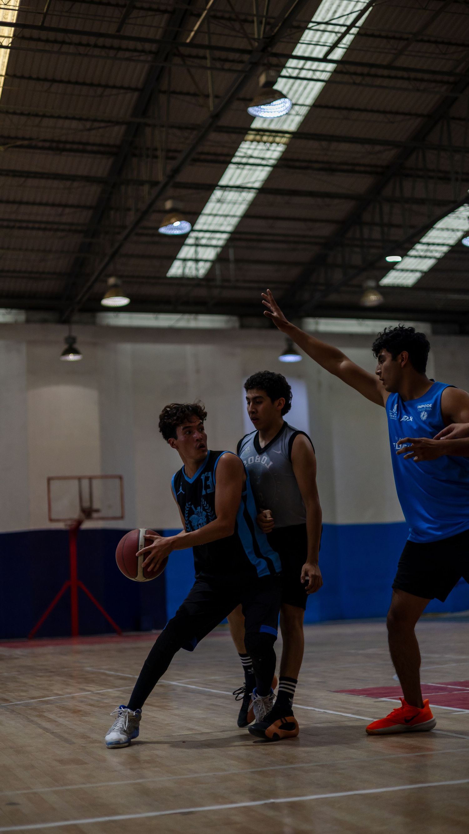 Basketball players compete in an indoor court during an intense game.