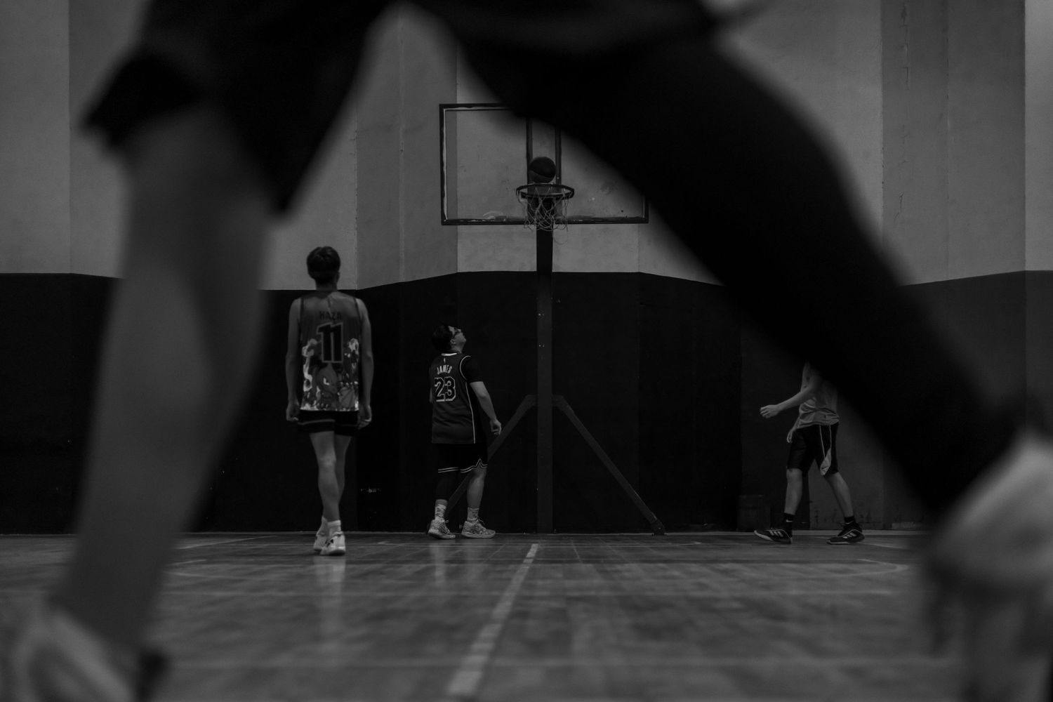 A black and white shot of basketball players on an indoor court during practice.