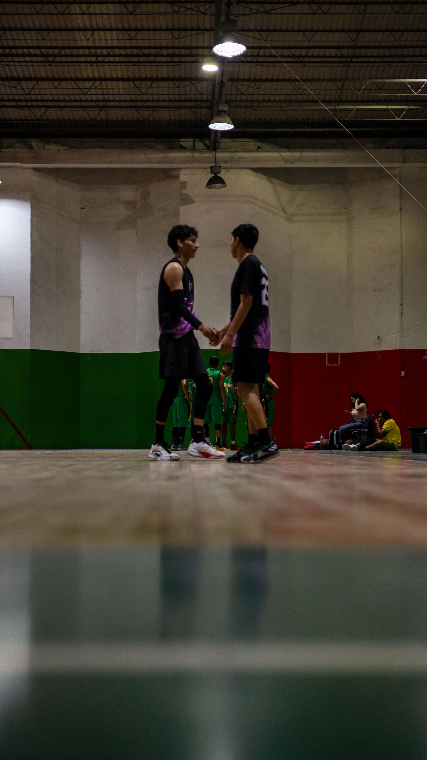 Indoor sports facility showing multiple people practicing in a dimly lit gymnasium space.