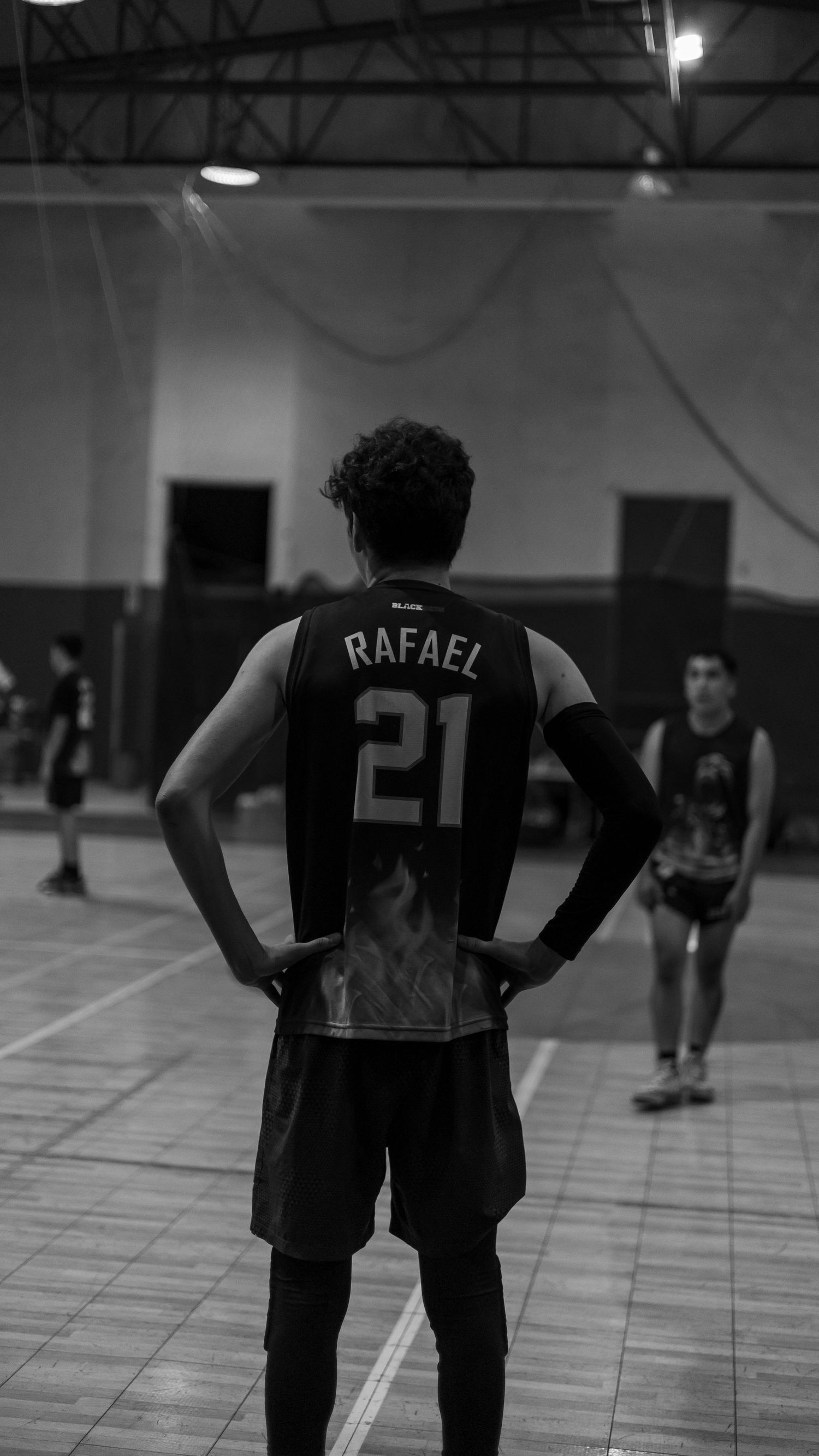 Athletes in numbered jerseys practicing in an indoor sports facility.