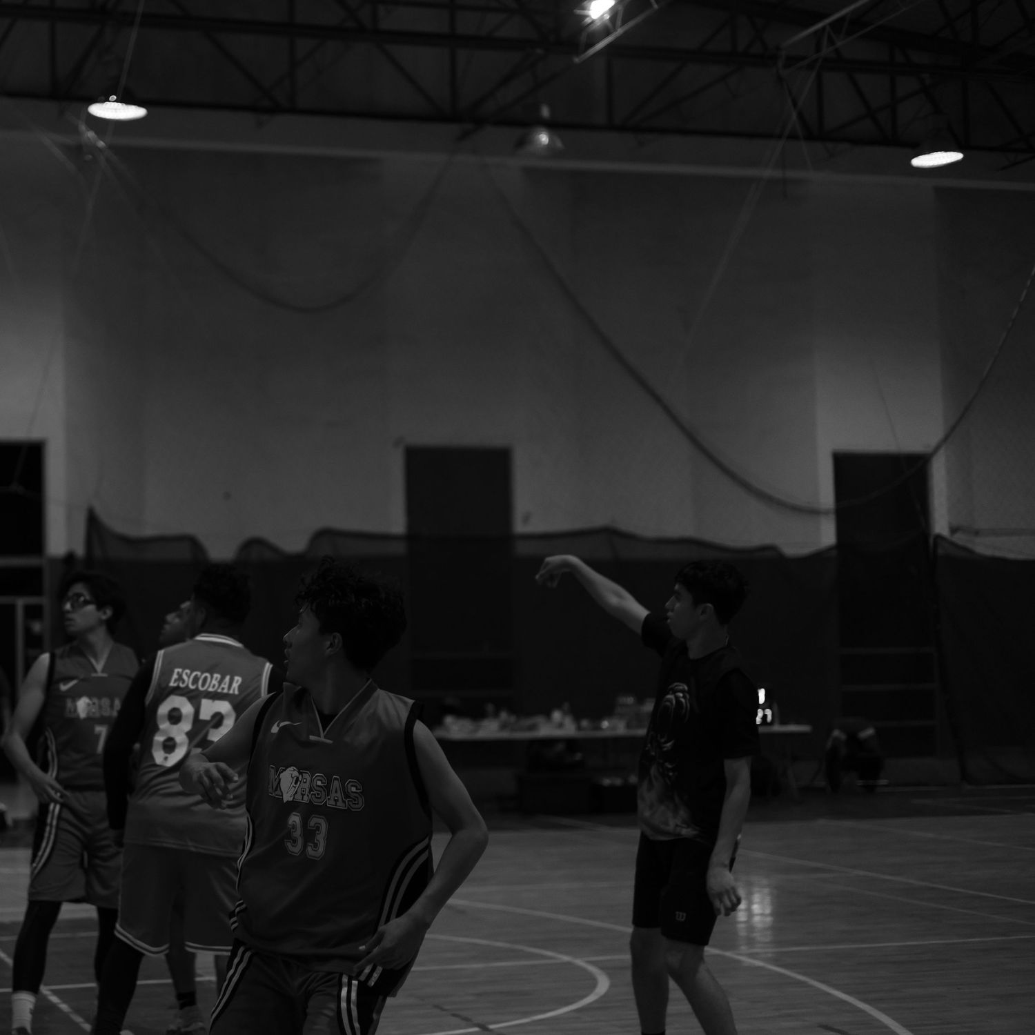 Basketball players in numbered jerseys practicing drills on an indoor court.