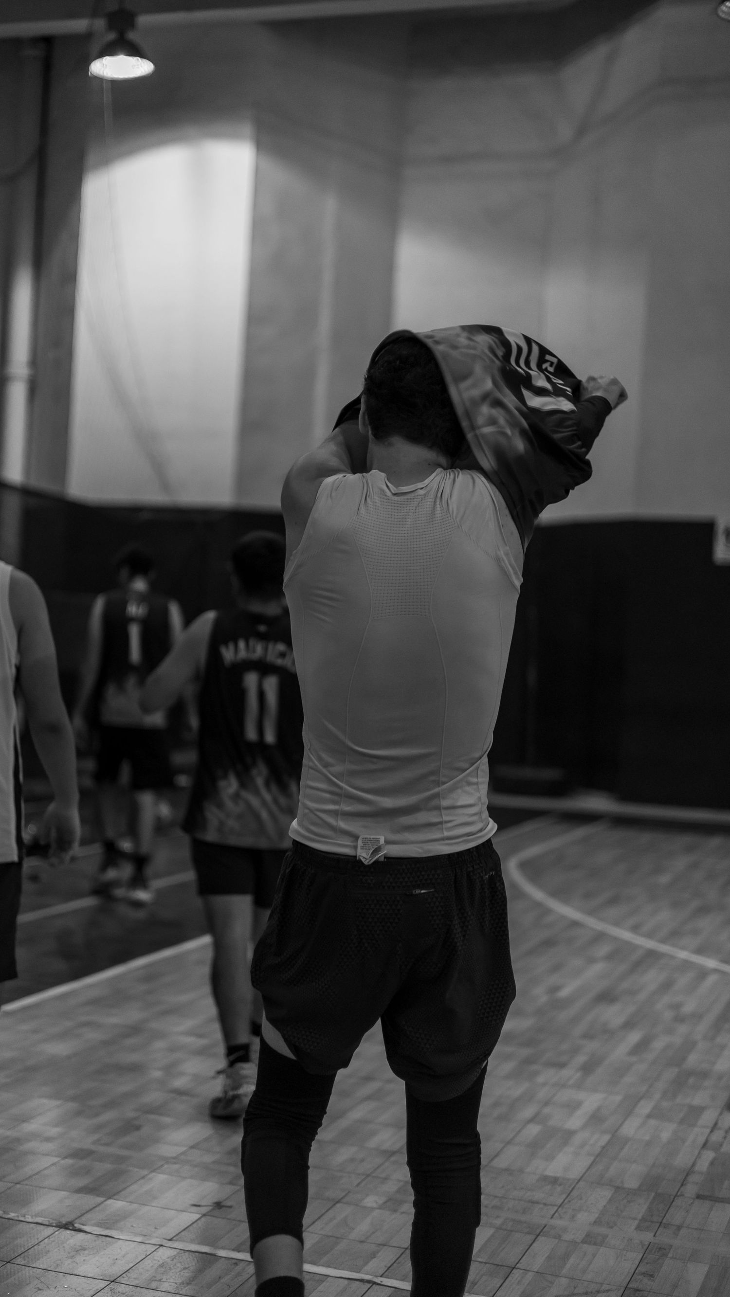 Athletes performing stretching exercises during practice in an indoor gym.