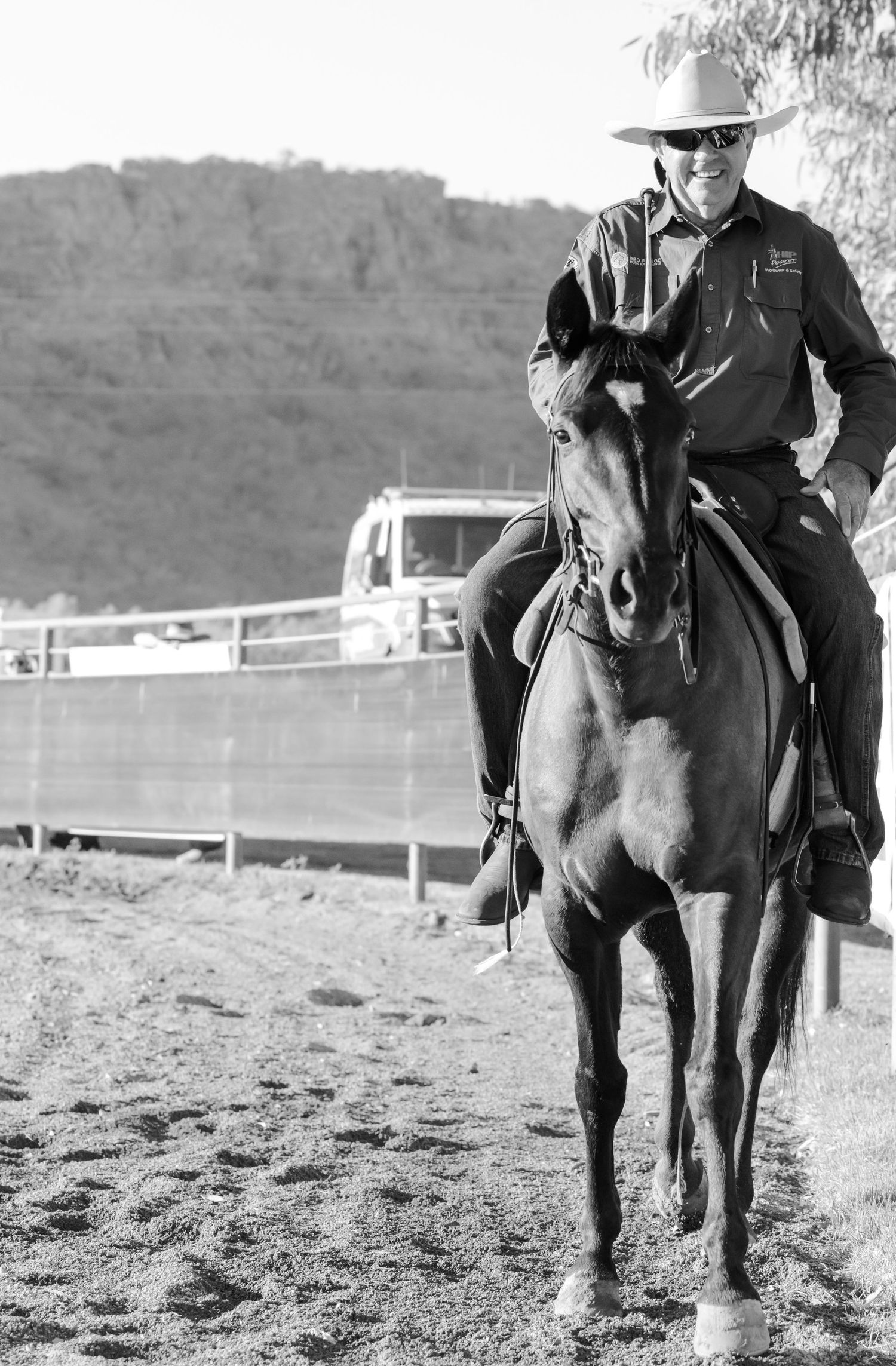 A rider on horseback in western gear photographed in black and white.