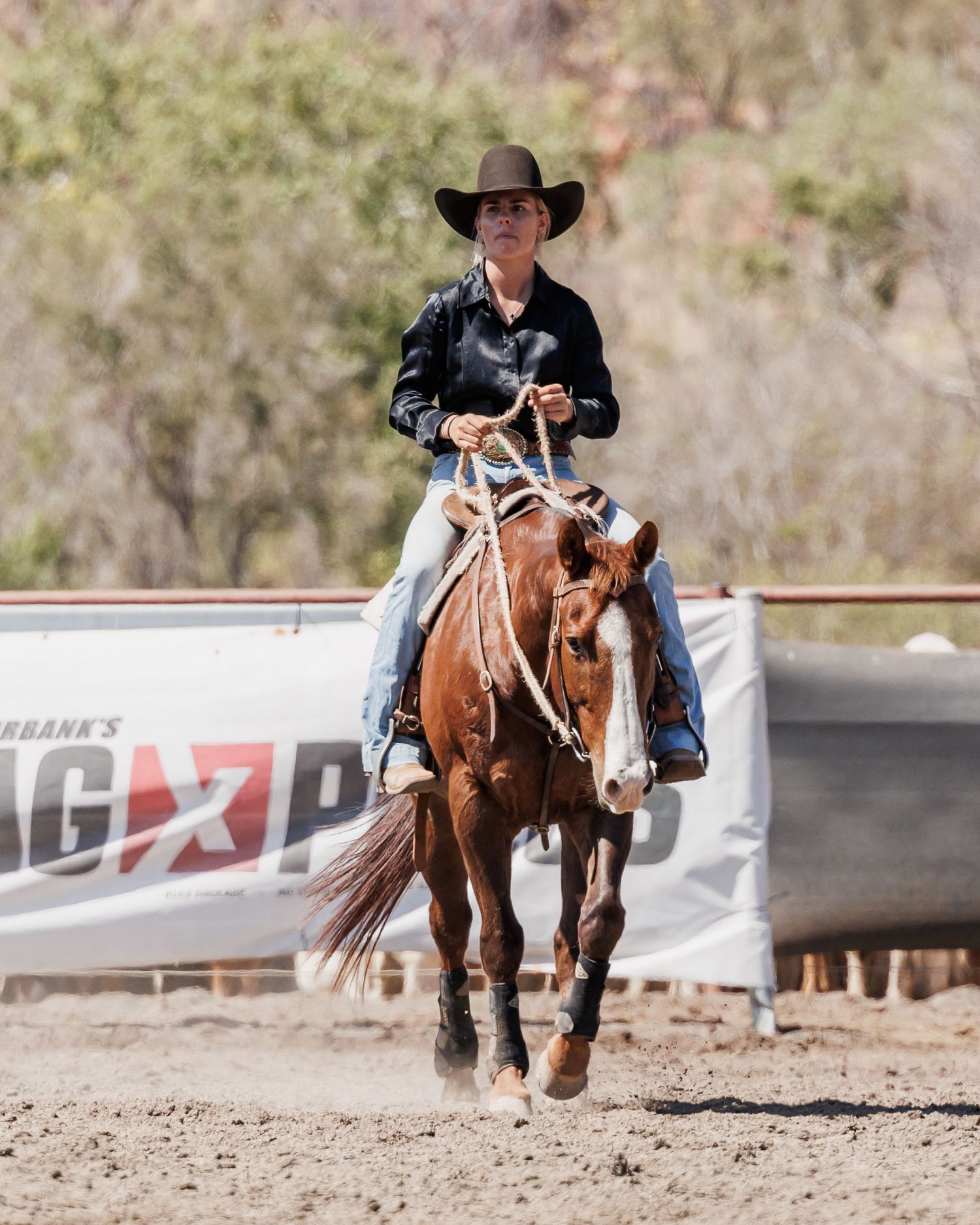 A cowboy competes in a western riding event on a chestnut horse in an arena.
