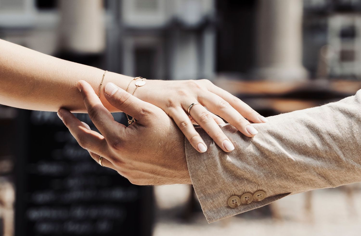 Close-up of hands touching with an engagement ring visible in soft lighting.