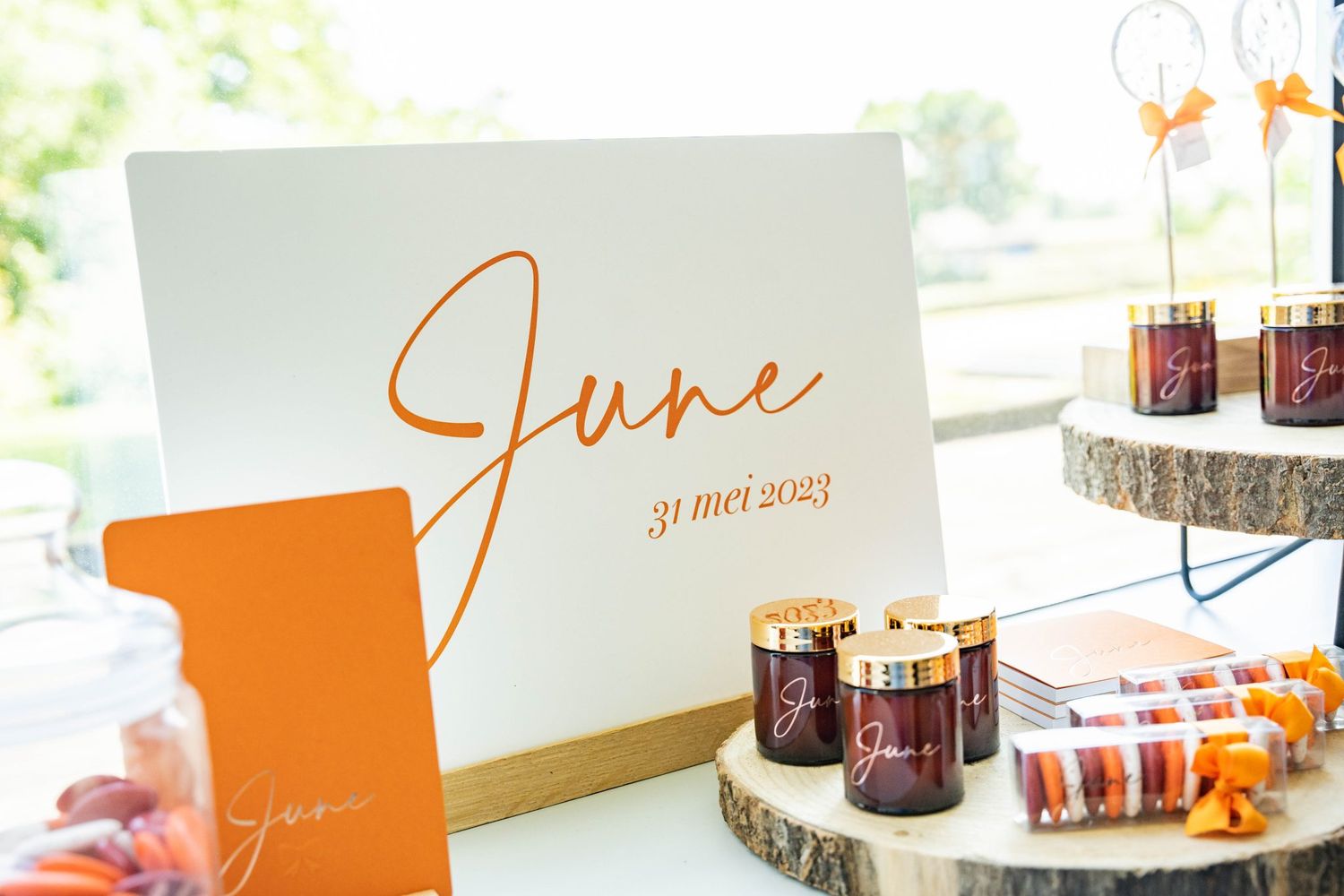 Orange and white event signage display with June text and decorative candle holders.