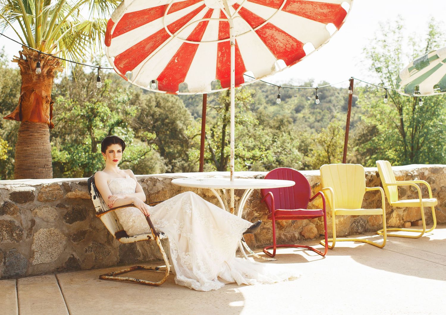 Wedding scene with striped red and white umbrella on sunny patio with retro furniture.