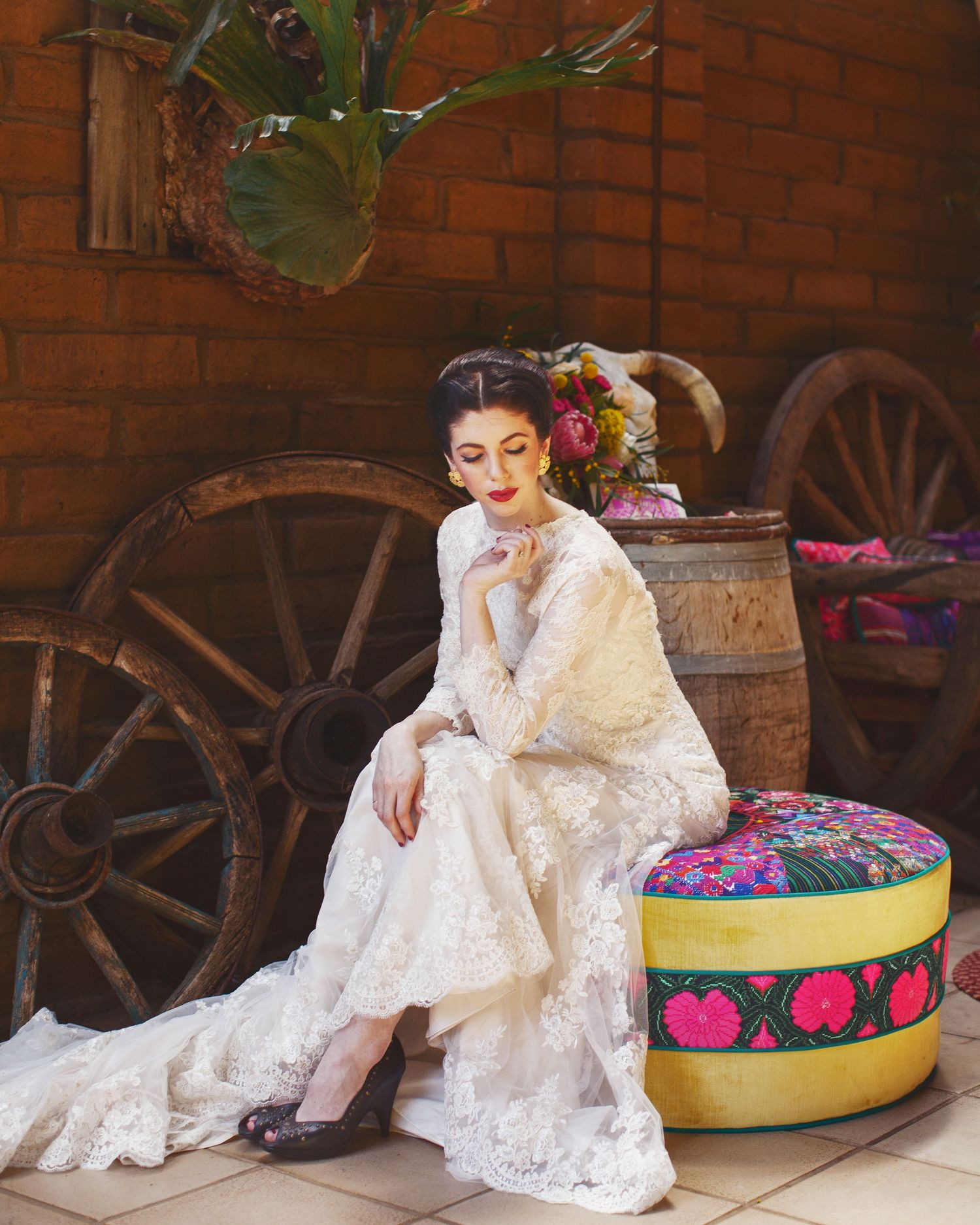 Vintage-style bridal portrait with rustic wooden wagon wheels and barrel backdrop.