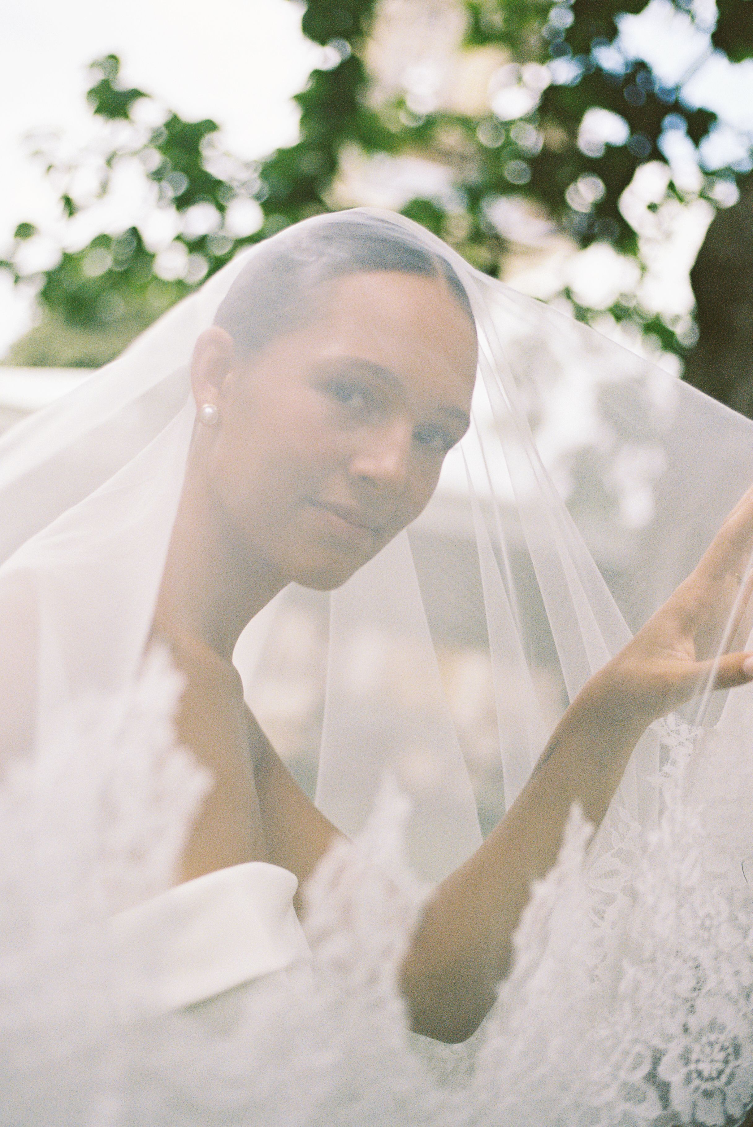 An ethereal bridal portrait through a delicate veil in soft natural light.
