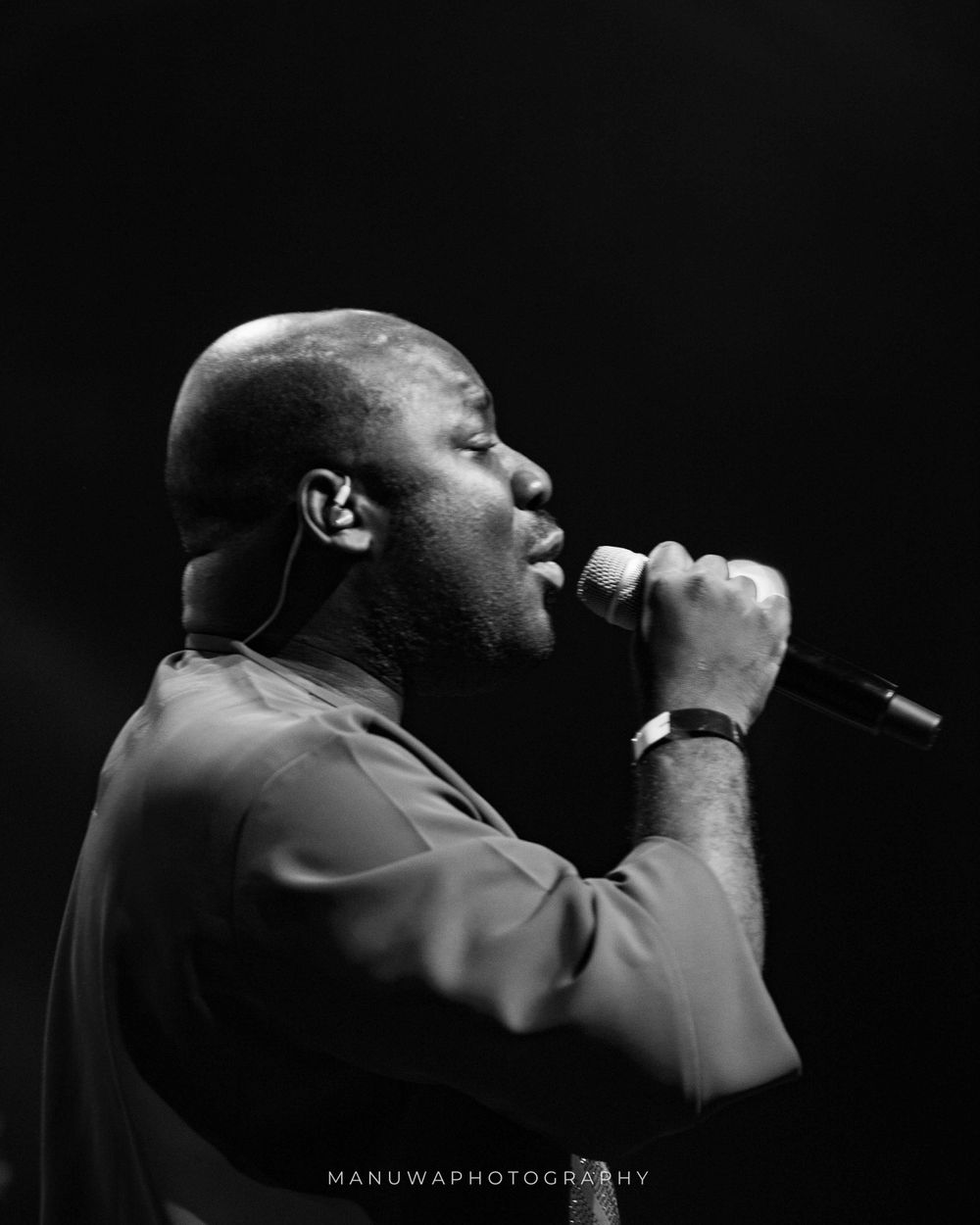 Side profile of singer performing emotionally in black and white.