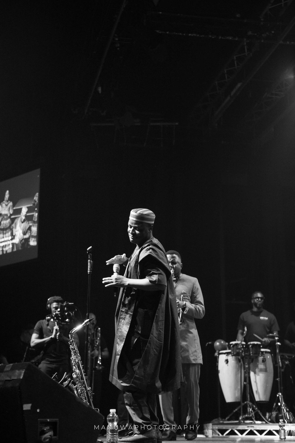 Dramatic black and white stage performance with saxophone player and percussion section.