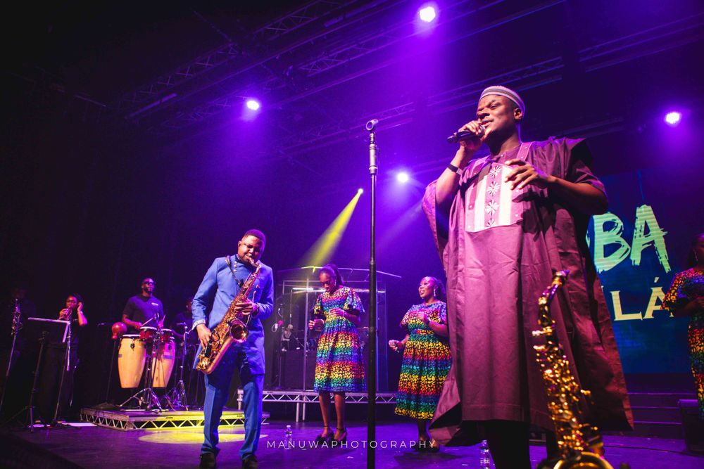 Energetic stage performance with band members in colorful costumes under purple stage lighting.