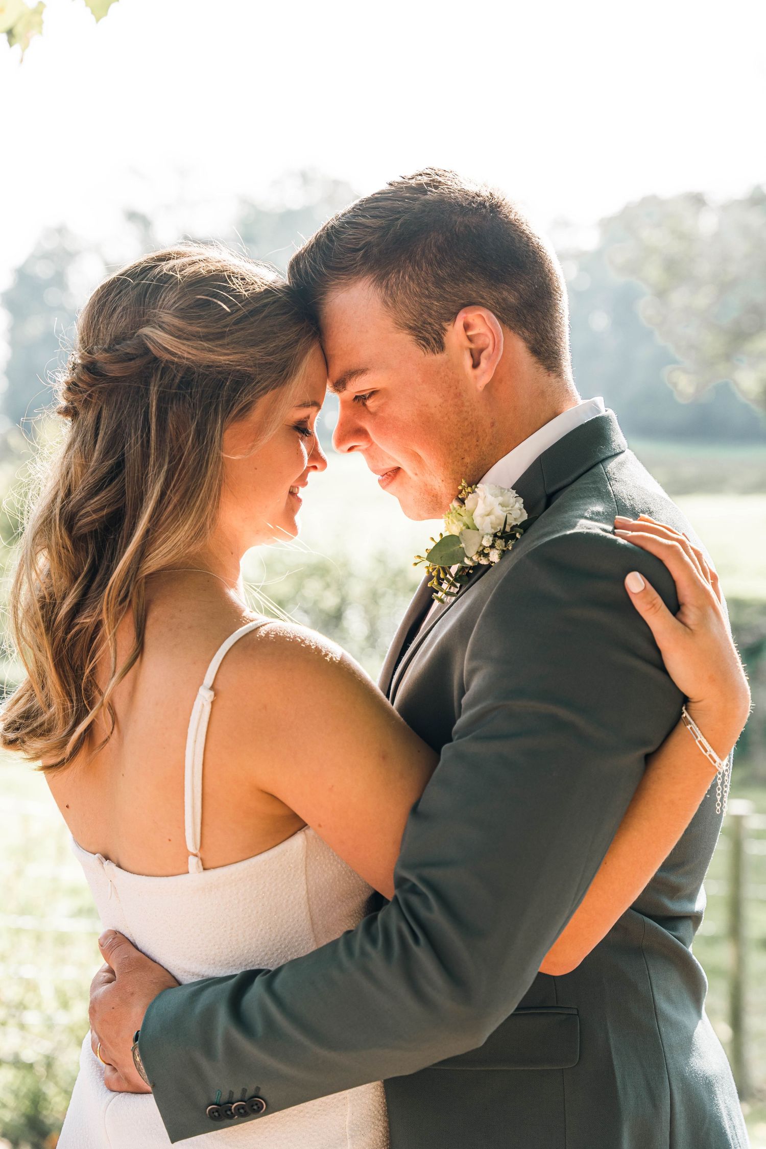 A tender embrace between newlyweds in formal attire during golden hour outdoor photography.