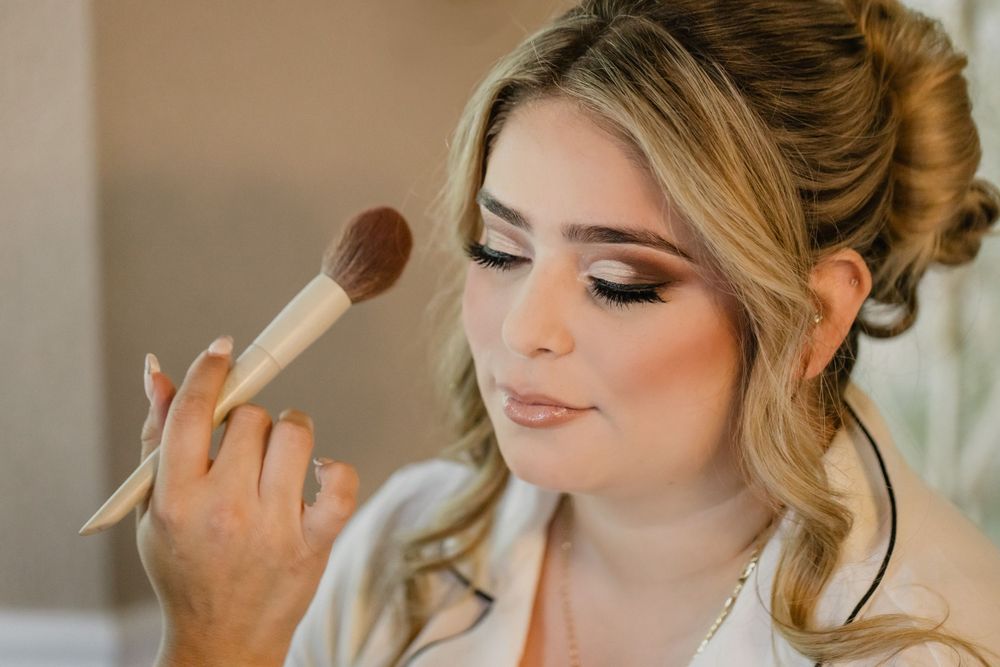 Wedding makeup artist applying eye makeup using a professional brush.