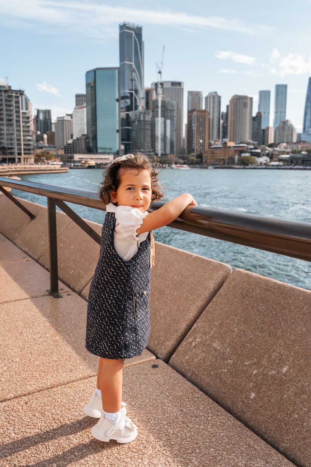 Adorable toddler peeking at a fence in Sydney city during a photoshoot, capturing a moment in the urban backdrop