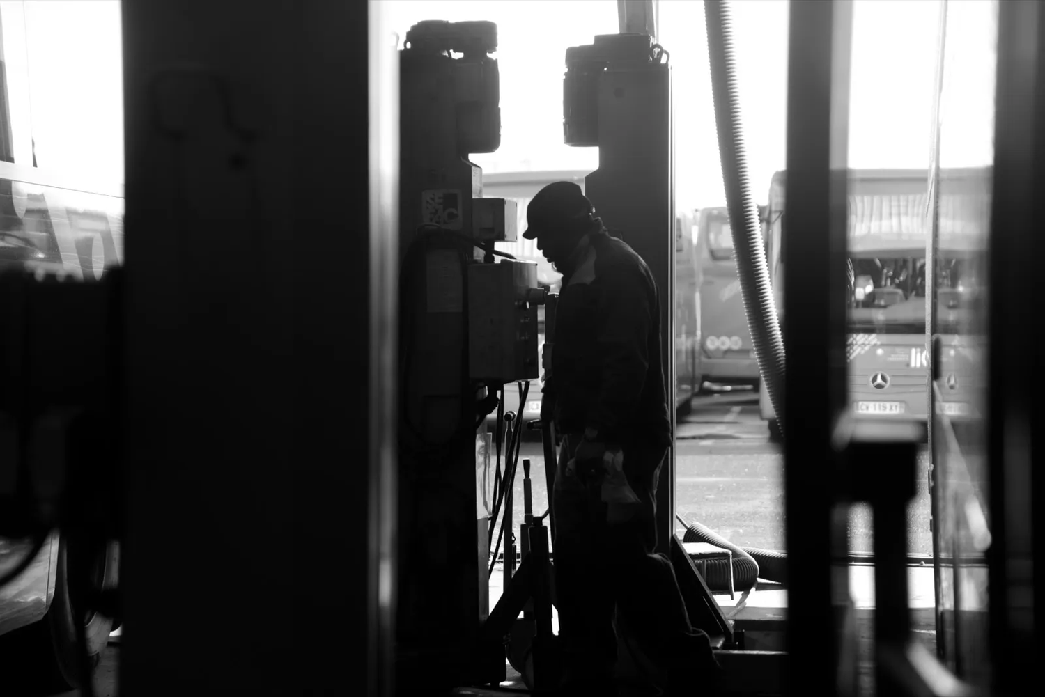Ombre d’un travailleur dans un garage ou atelier, entouré de machines, lumière naturelle entrant par les vitres.