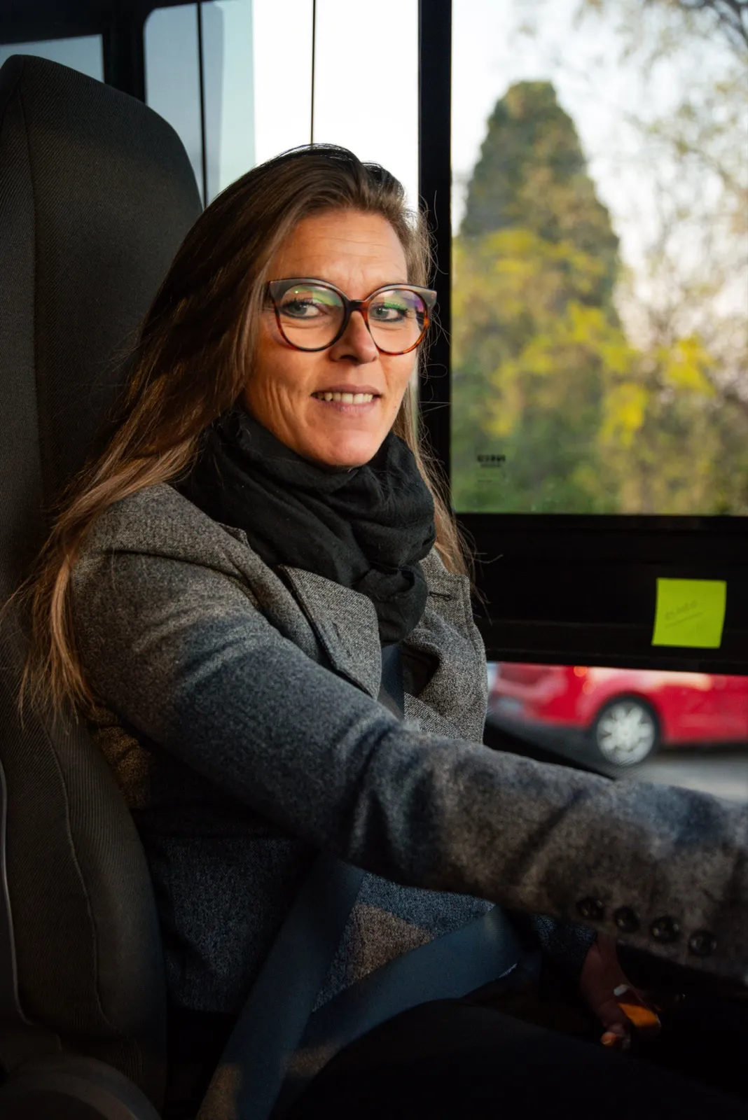 Portrait d’une femme au volant d’un bus, regardant par la fenêtre avec assurance et professionnalisme.