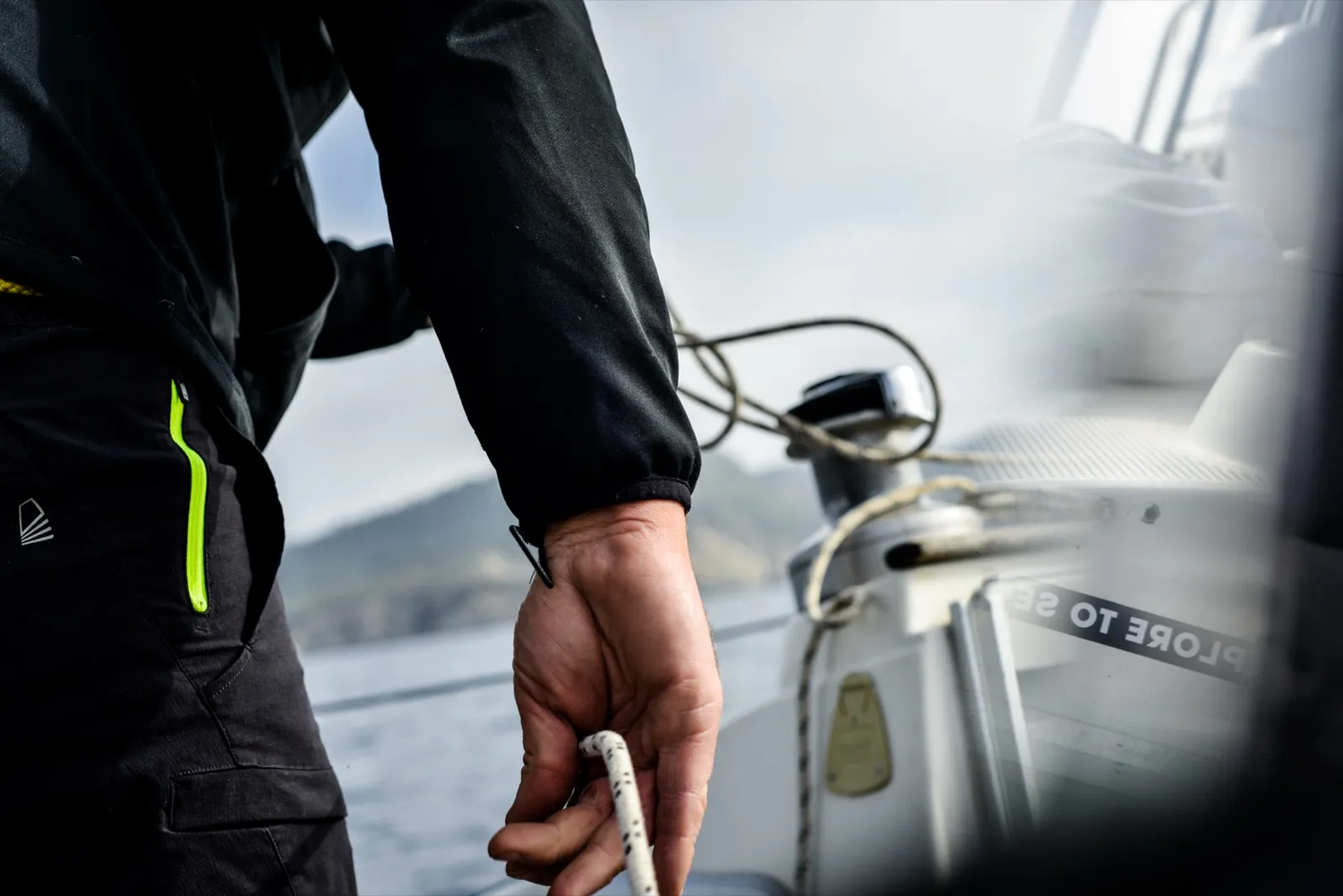 Main d’un marin en gros plan, tenant un cordage sur un winch.