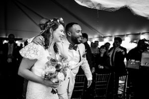 Black and white photo of smiling bride and groom walking together after wedding ceremony.