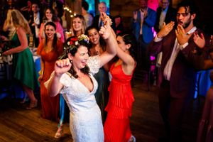 Bride dances joyfully with guests at a lively rustic barn wedding reception.