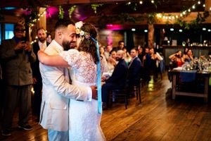 Bride and groom share their first dance in a warmly lit rustic barn wedding venue.