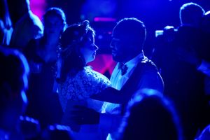 Bride and groom share romantic slow dance bathed in blue light at wedding.