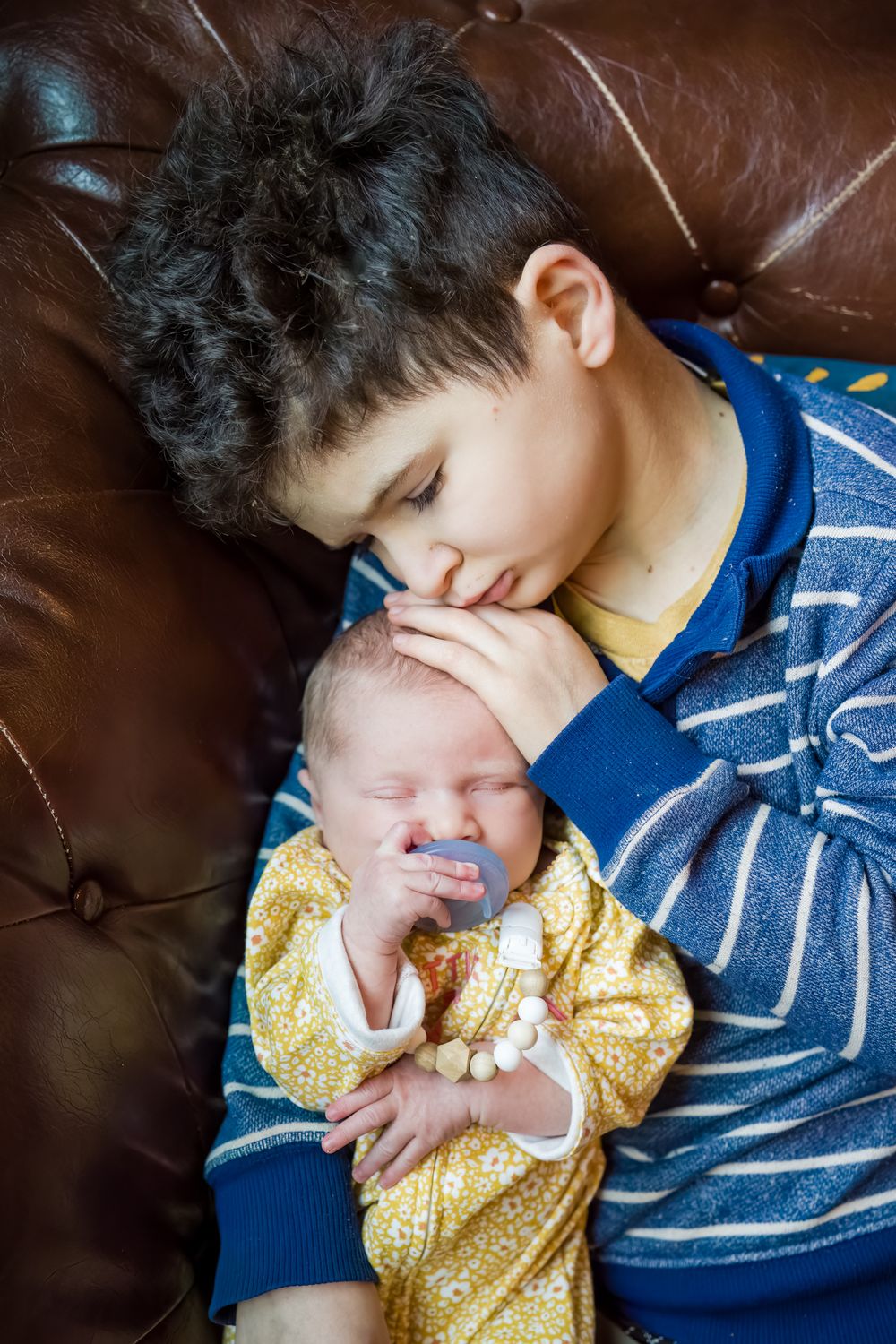 boy holds newborn girl on the couch