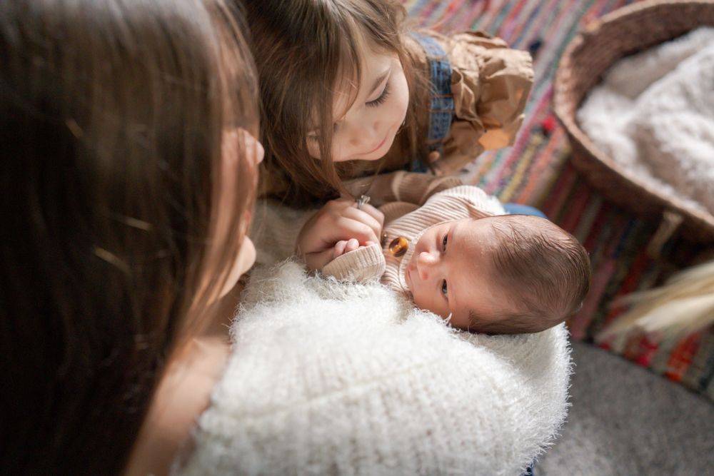 baby boy looks up at mom and big sister