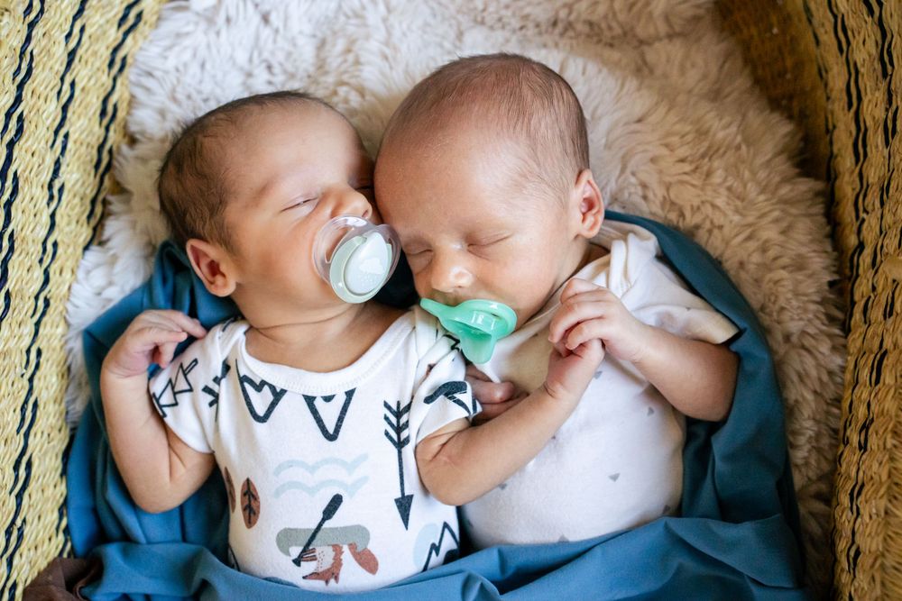 twin boys cuddle while they sleep and hold hands