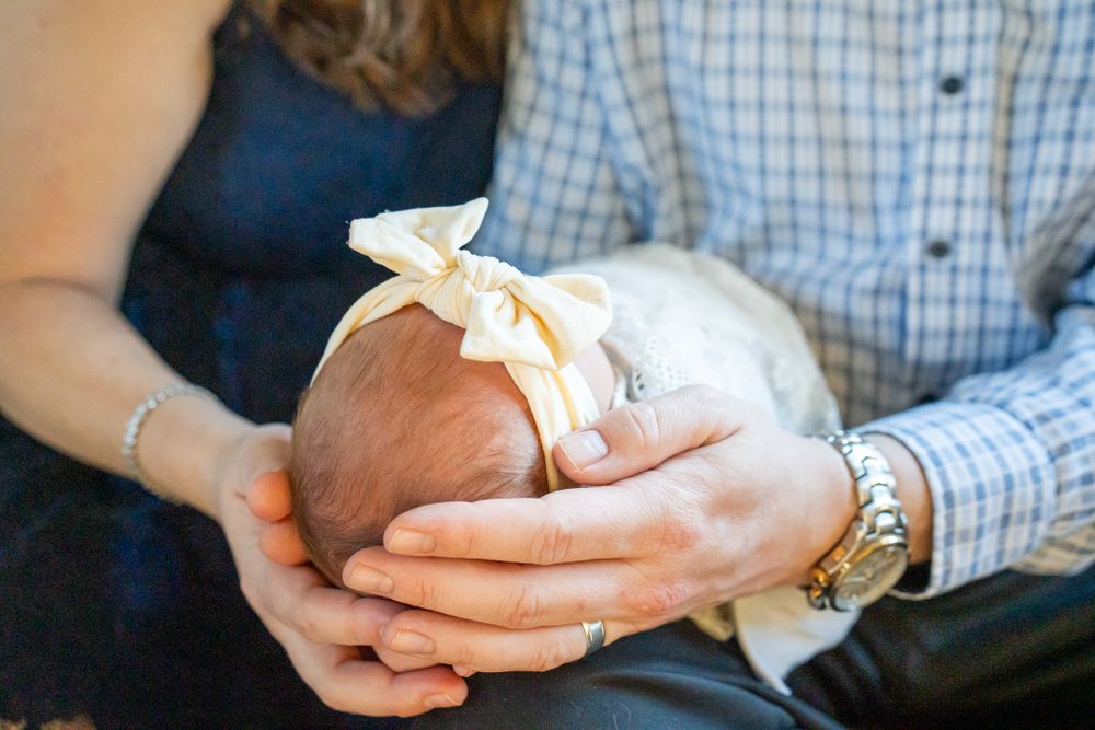 mom and dad cup newborn daughter's head
