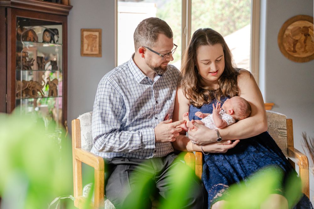 mom and dad hold newborn daughter while relaxing at home