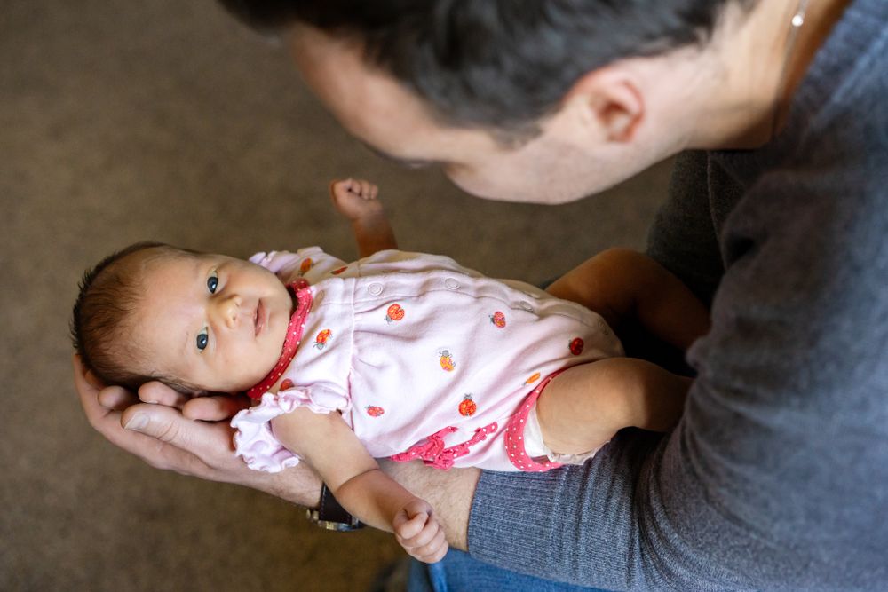 dad holds newborn daughter while looking at her