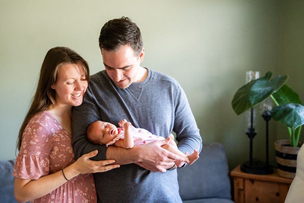 mom and dad hold newborn daughter
