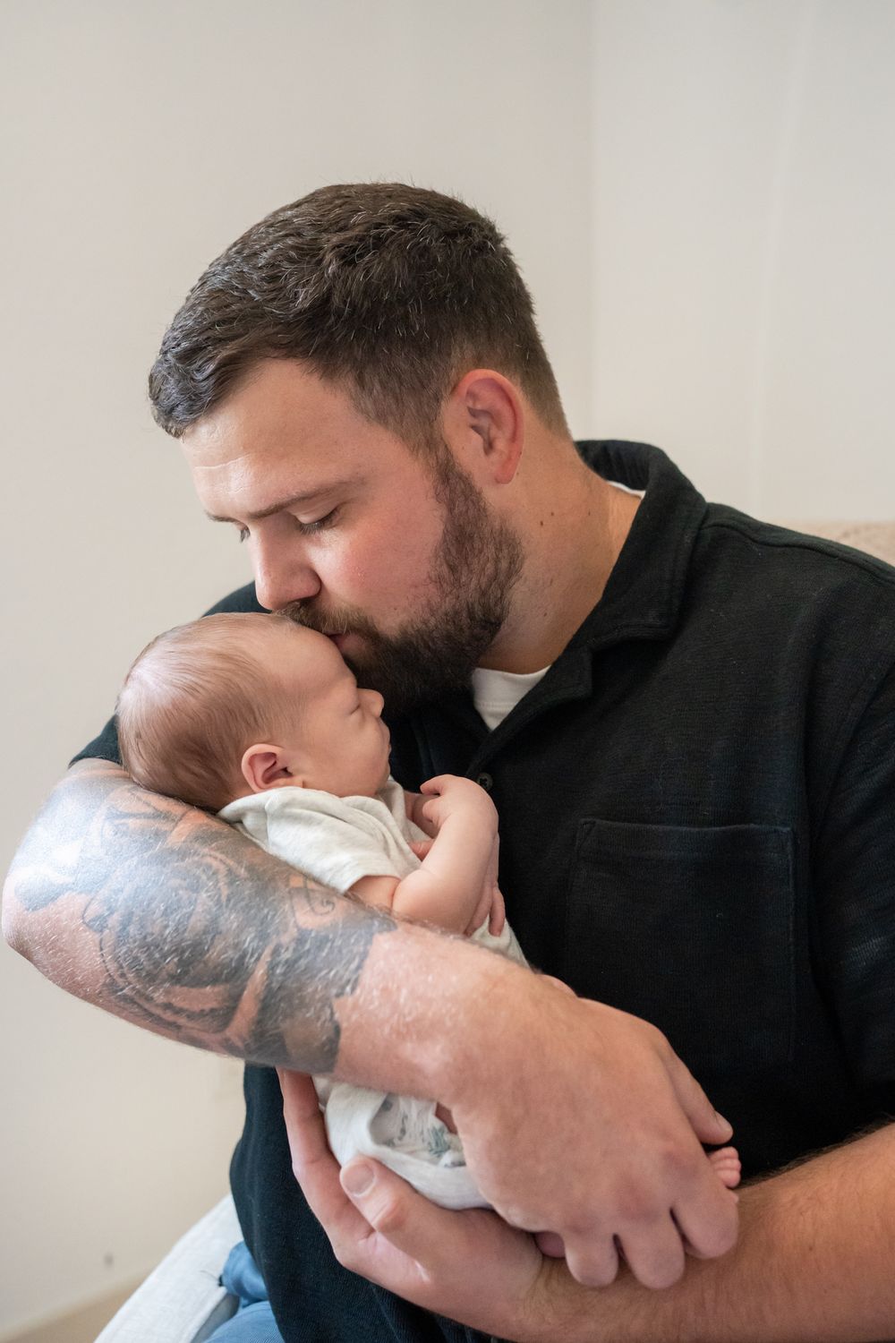 dad kisses newborn son on the forehead portrait