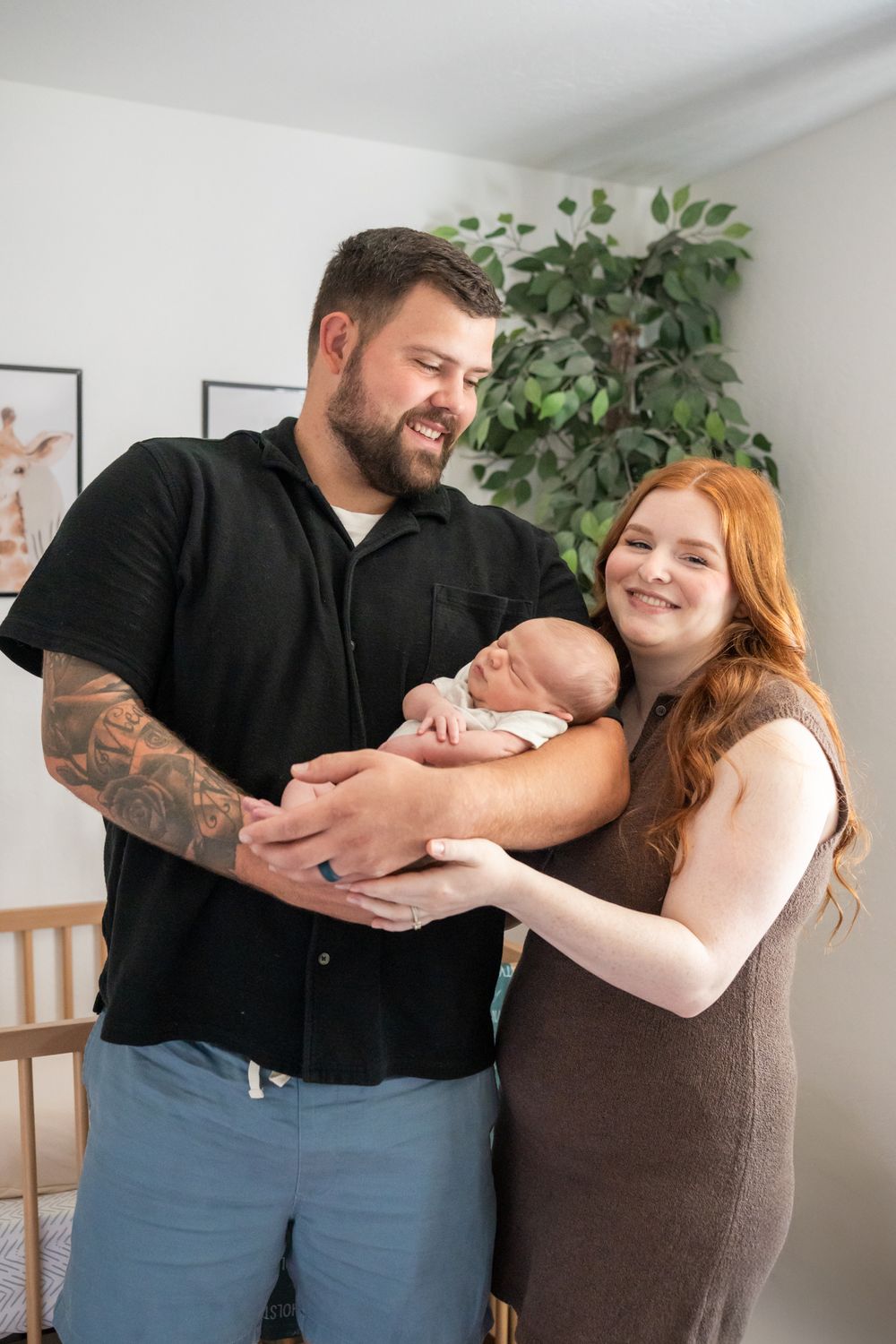 mom and dad and newborn son family portrait in the baby's nursery