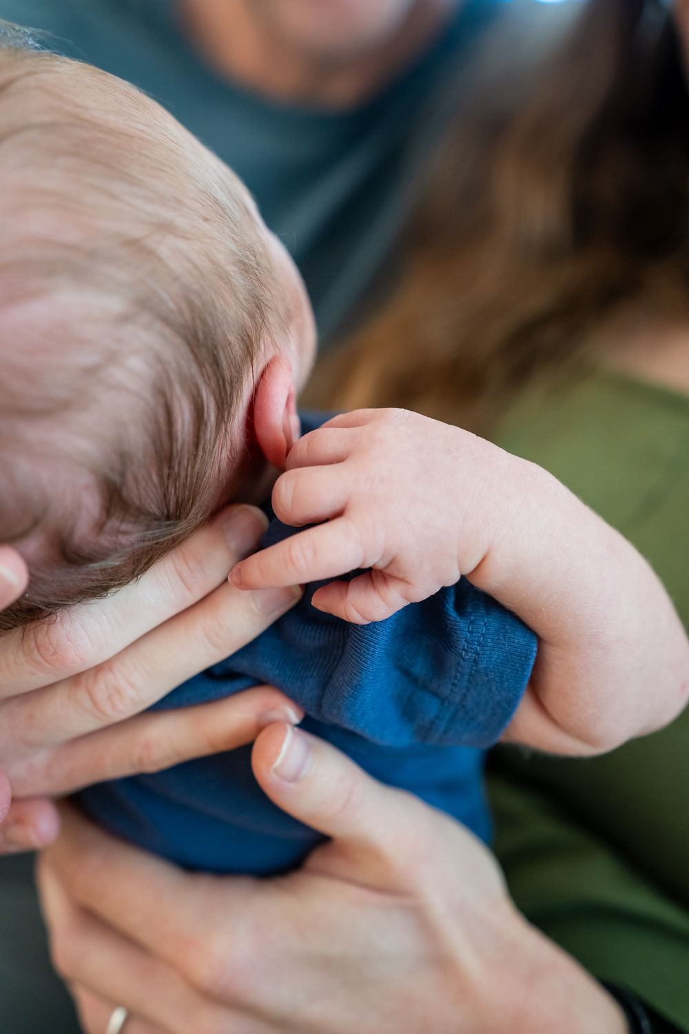 baby boy reaches back as mom holds him