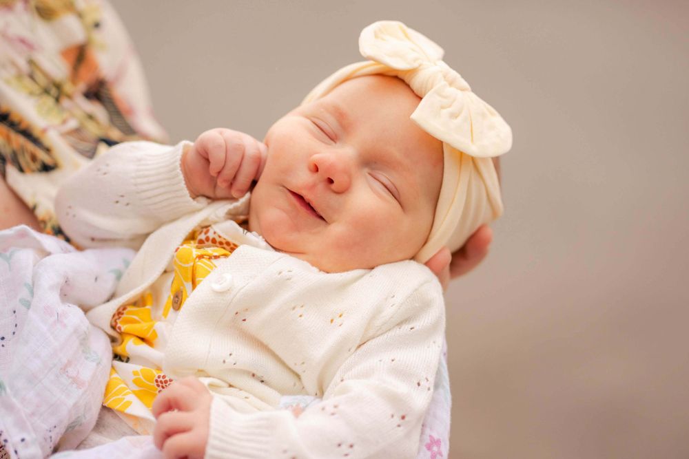 newborn daughter smiles while mom holds her