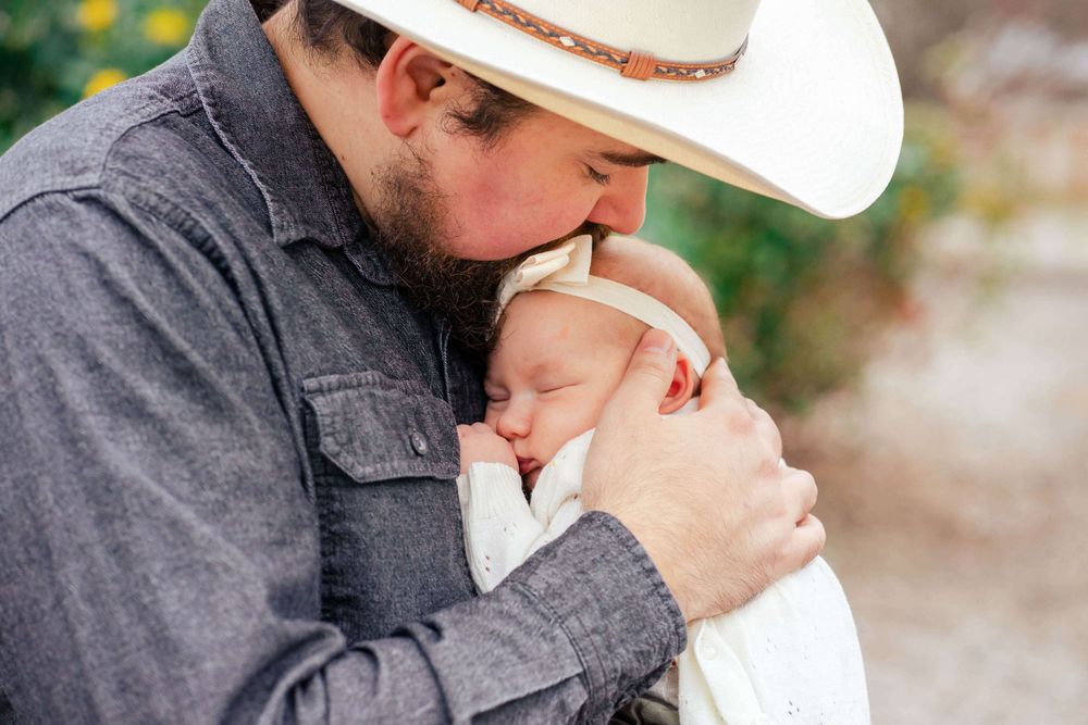 dad kisses newborn daughter