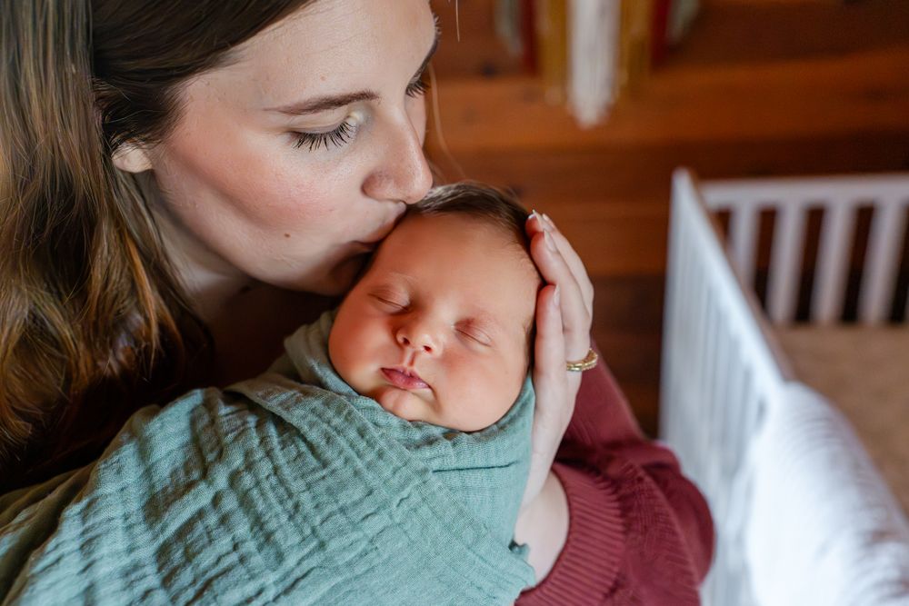 mom kisses newborn daughter