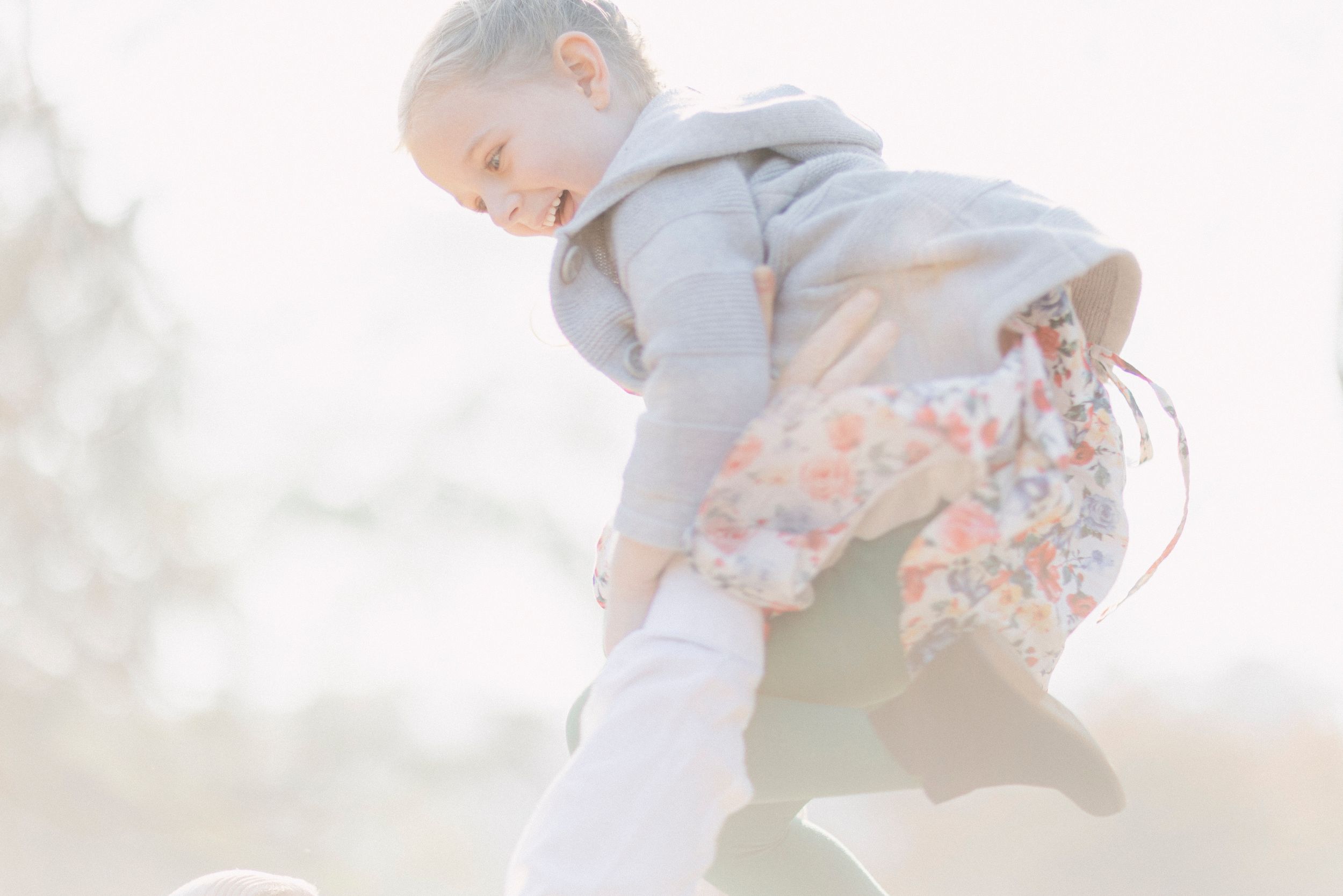 A candid action shot of someone in a gray hoodie and floral dress playing outside.