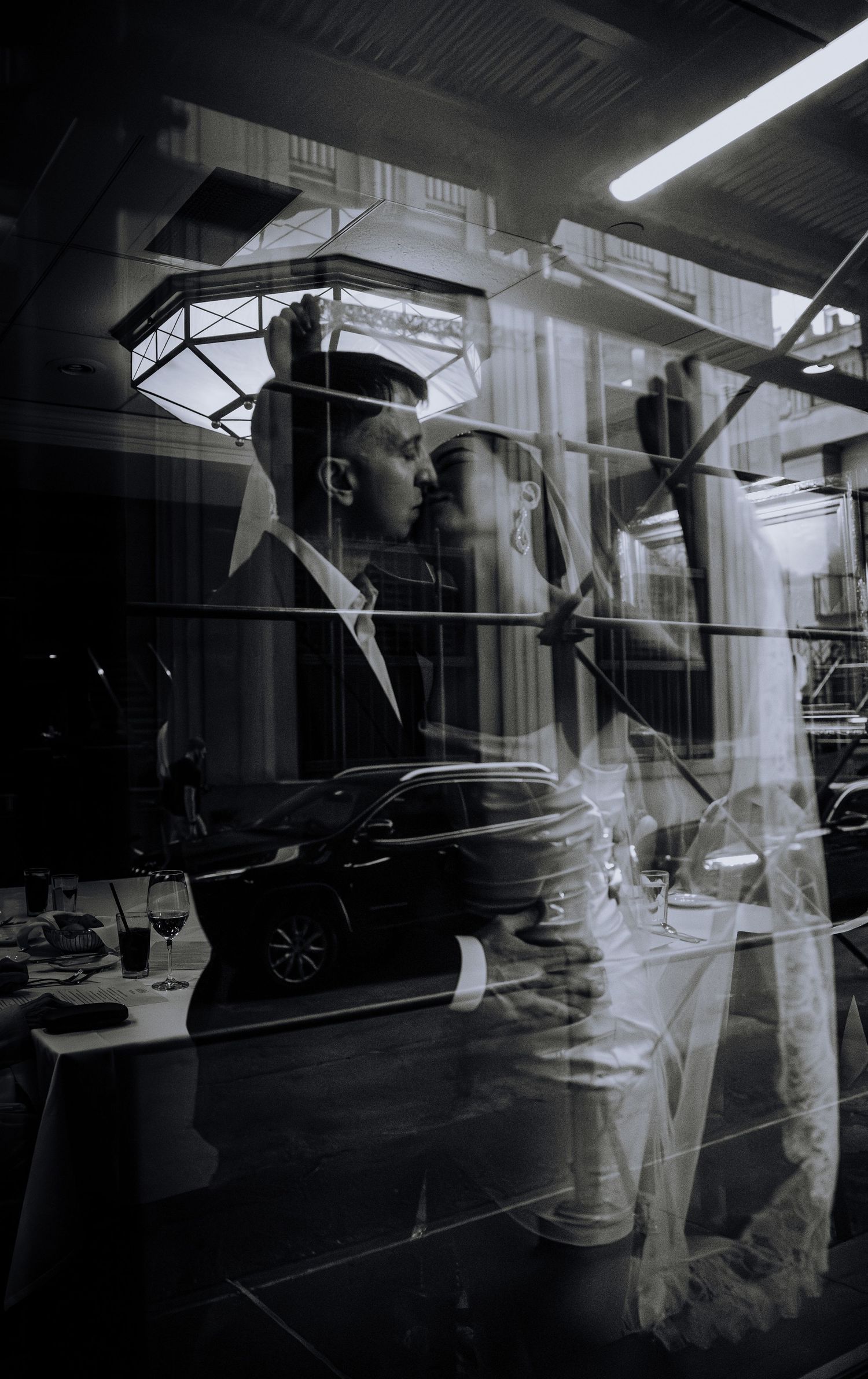 Black and white double exposure photograph of architectural details and a car reflection through glass window in New York.